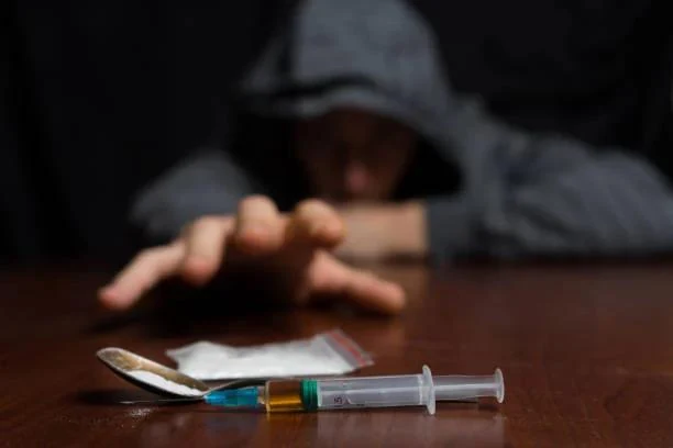 Awareness photograph of a person reaching toward drug paraphernalia